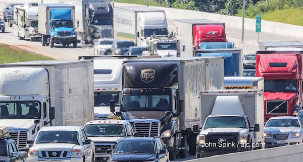 A fiery tractor-trailer crash on I-75 north of Wade Green Road blocked the interstate for hours. The truck went through a sound barrier wall on I-75, officials said. JOHN SPINK / JSPINK@AJC.COM