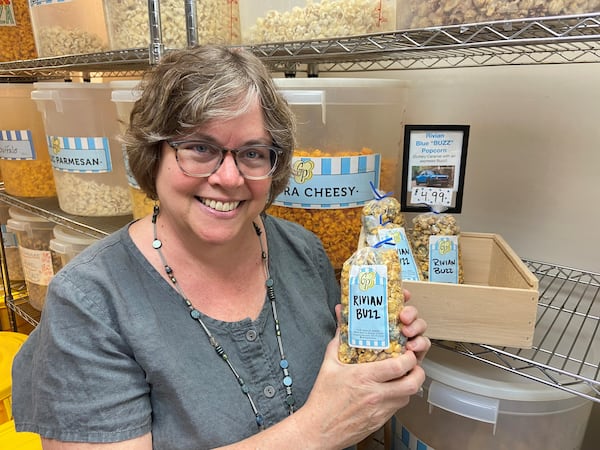 Sarah McManus, a co-owner of The Garlic Press in Uptown Normal, poses inside the popcorn section of her store with 'Rivian Buzz' popcorn she made.