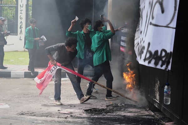 Student protesters burn a tire and throw objects at police officers during a rally against the passing of a new military law allowing active military personnel to hold more civilian posts, outside the parliament in Jakarta, Indonesia, Thursday, March 20, 2025. (AP Photo/Tatan Syuflana)