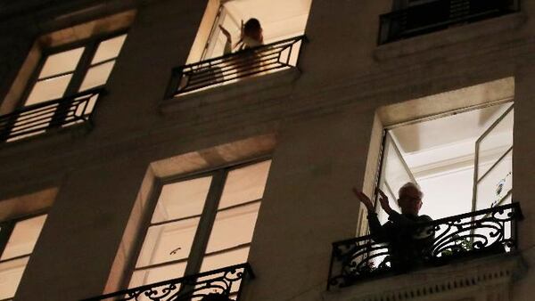 People applaud the caregivers for their work, as the coronavirus ravaged communities across the country, in Paris, Friday, March 20, 2020. Paris police imposed a ban for the weekend on the Seine River banks. (AP Photo/Michel Euler)