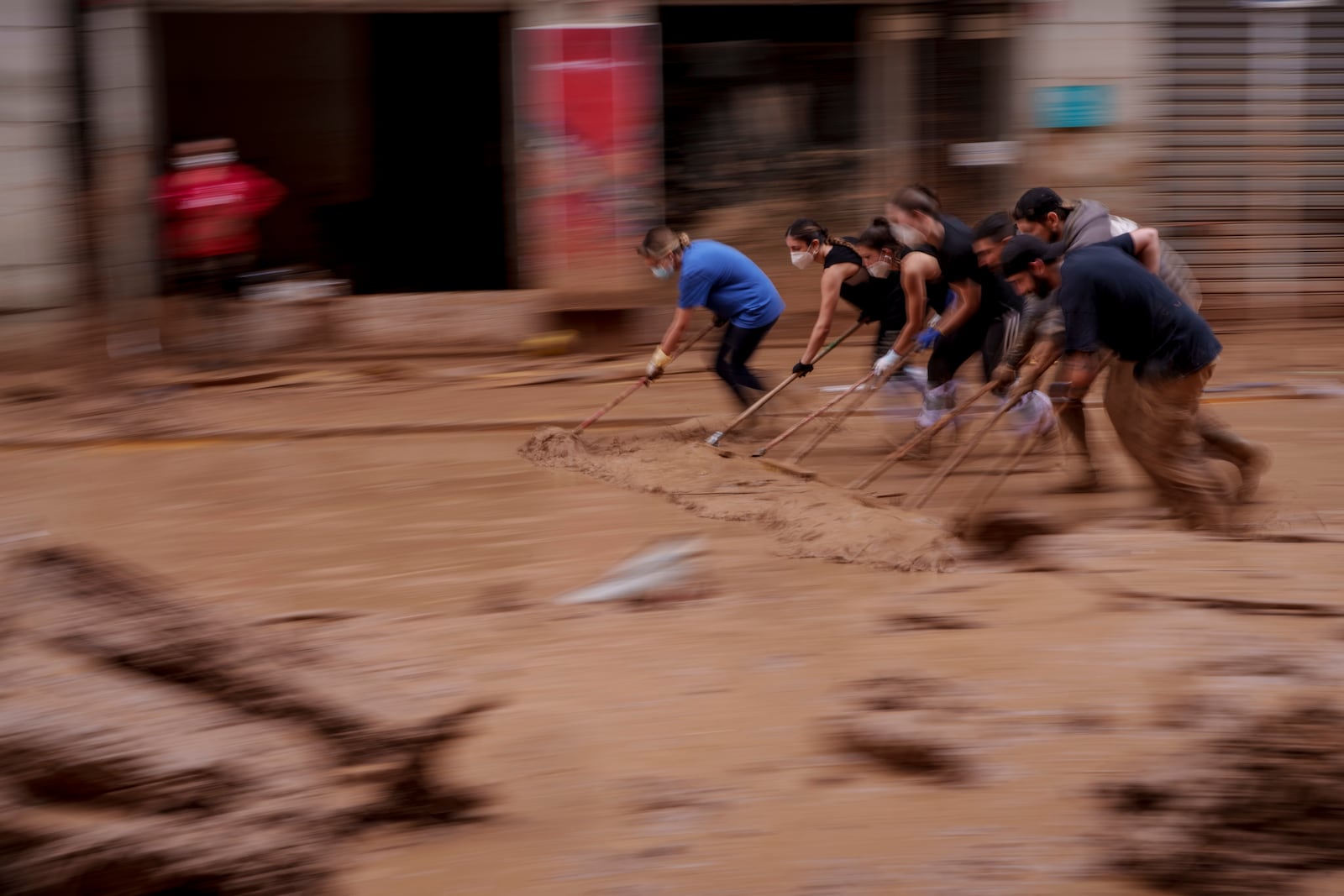 People clear mud from a street in an area affected by floods in Catarroja, Spain, on Monday, Nov. 4, 2024. (AP Photo/Manu Fernandez)