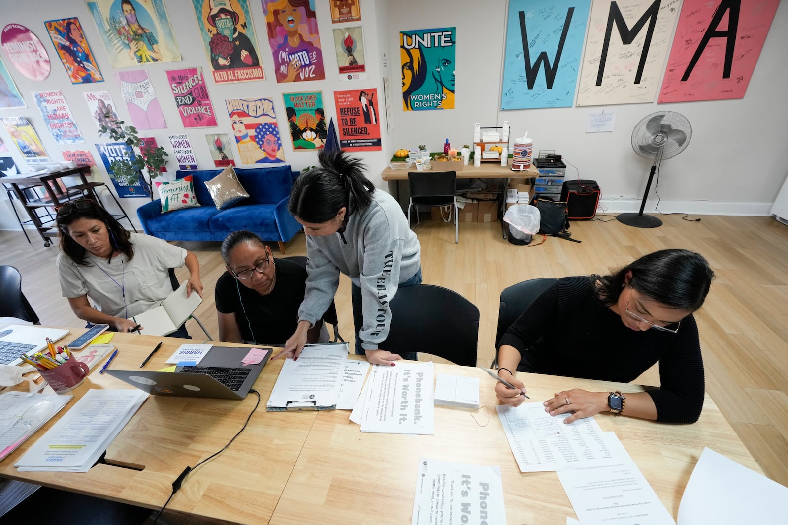 Emiliana Guereca, founder and president of the Women's March Foundation, left, works at a phone bank calling voters to encourage them to vote for Democratic presidential nominee Vice President Kamala Harris with volunteers, Rosalba Serna, second from left, Mirian Palacios and Ivette Aragon, right, on Tuesday, Oct. 15, 2024, in Los Angeles. (AP Photo/Damian Dovarganes)