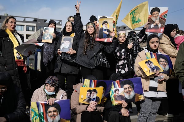 Mourners hold pictures of Hezbollah's former leader Hassan Nasrallah and his cousin and successor Hashem Safieddine as they gather along a highway to attend their funeral procession in Beirut, Lebanon, Sunday Feb. 23, 2025. (AP Photo/Bilal Hussein)