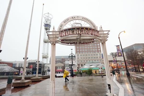 A person makes his way through the rain in front of the Marta Station at Underground Atlanta on Thursday, December 30, 2021. Heavy rain fell overnight and continued through the morning. The Metro Atlanta area was under warning for severe thunderstorms and flash floods. Miguel Martinez for The Atlanta Journal-Constitution 