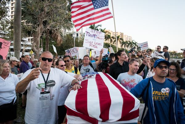 Protesters push a casket representing the "Death of Democracy" down Flagler Drive in West Palm Beach as President Donald Trump and his wife Melania attend the 60th annual Red Cross Ball at the Mar-a-Lago on Saturday Feb. 4, 2017.