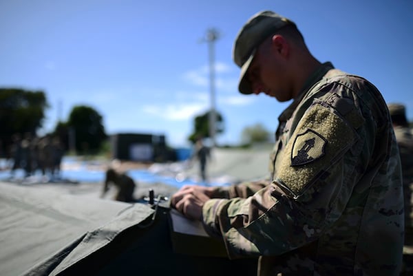 A member of the U.S. Army Reserve works to set up portable showers in a tent city for hundreds of people displaced by earthquakes in Guanica, Puerto Rico.