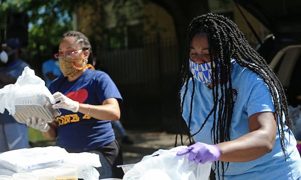 Tammy Tamer bags food during the Grab and Go free food and groceries event on Friday, April 17, 2020, at Allen Hills Apartments in Atlanta. The community effort to help families during the coronavirus pandemic was led by the Fulton County district attorney’s office. (Christina Matacotta, for The Atlanta Journal-Constitution)