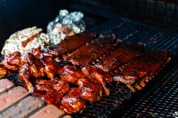 Chicken and ribs cooking on the titular brick pit at Old Brick Pit Barbecue. CONTRIBUTED BY HENRI HOLLIS