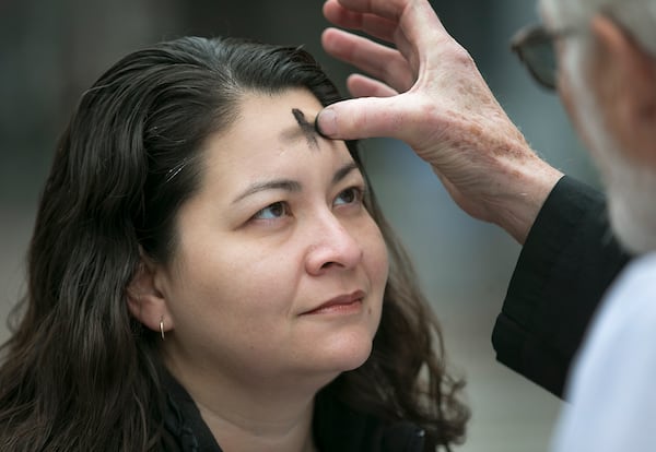 A minister administers the imposition of ashes to signify repentance and the start of the Lenten season.