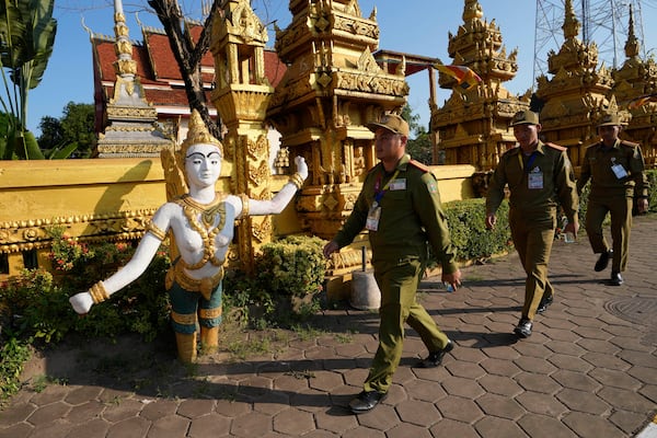 FILE- Laos policemen walk in front of Phon Tha Ya Ram Temple in Vientiane, Laos, Monday, Oct. 7, 2024. (AP Photo/Sakchai Lalit, File)