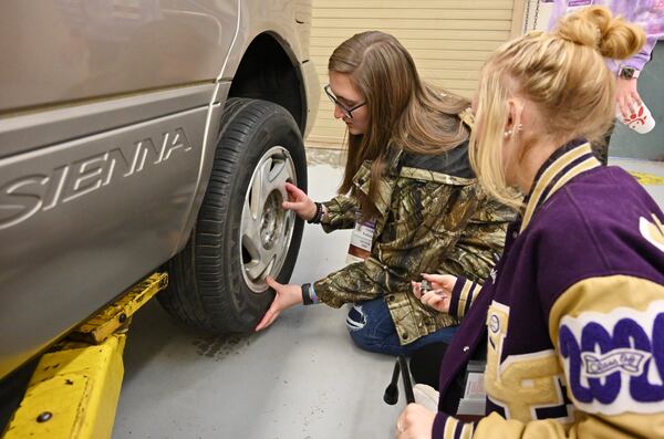 Seniors Natalie Robinson (left) and Evelyn Dornhecker (right) practice changing a tire during the second annual Senior Adulting Day at Lumpkin County High School in Dahlonega on Friday, Jan. 24, 2020. 