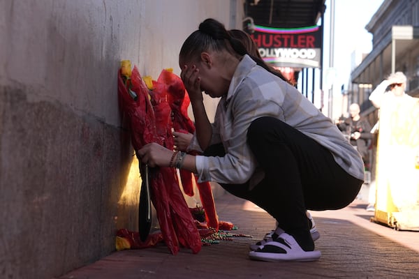 Samantha Petry places flowera at a memorial on Canal and Bourbon Street, Thursday, Jan. 2, 2025 in New Orleans. (AP Photo/George Walker IV)