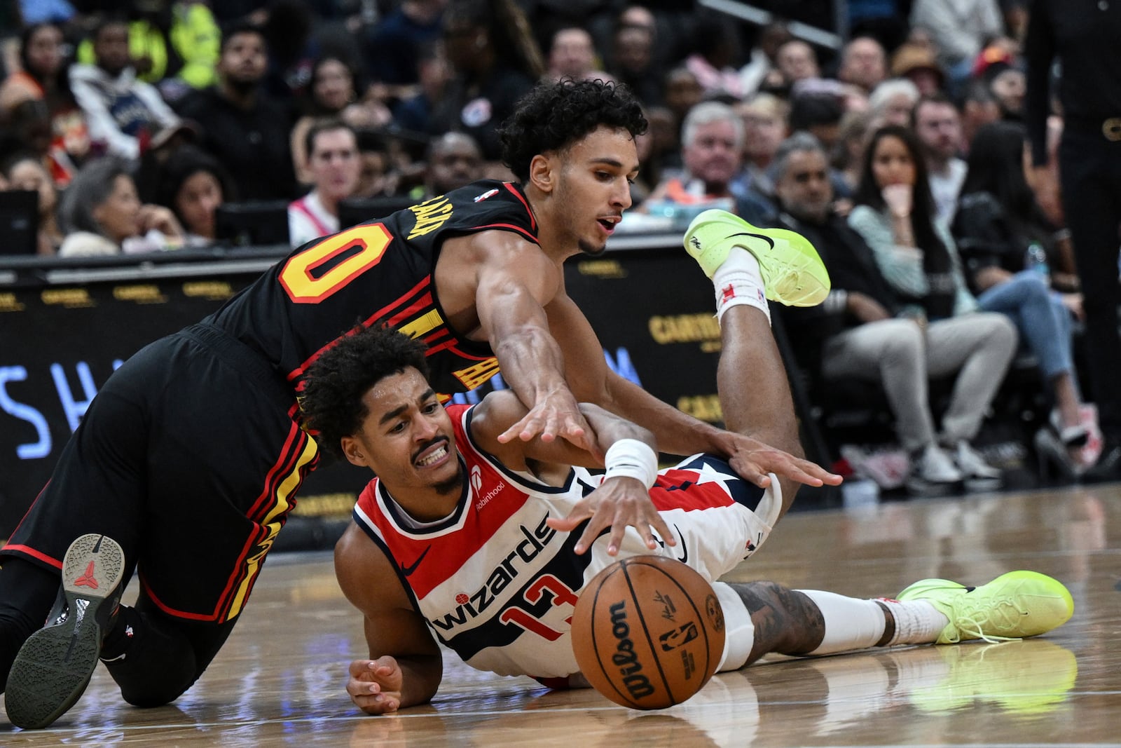 Atlanta Hawks forward Zaccharie Risacher and Washington Wizards guard Jordan Poole (13) compete for the loose ball during the first half of an NBA basketball game, Wednesday, Oct. 30, 2024, in Washington. (AP Photo/Terrance Williams)