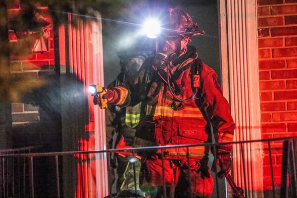 Firefighters canvas the area as they work to make sure residents are safe after an apartment fire. JOHN SPINK / JSPINK@AJC.COM