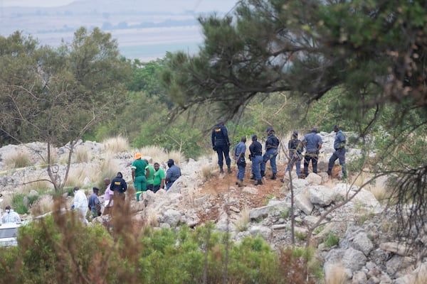 Rescue workers, bottom left, remove a body from a reformed mineshaft where illegal miners are trapped inside a disused mine in Stilfontein, South Africa, Thursday, Nov.14, 2024. (AP Photo/Jerome Delay)