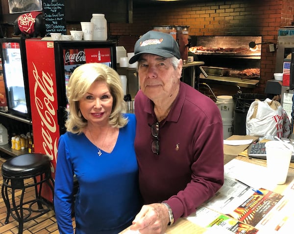 Old Hickory House proprietors George and Diane Jackson stand in front of their open fireplace-style pit at their restaurant in Tucker, the last outpost of a local barbecue chain that once had more than a dozen locations. CONTRIBUTED BY JIM AUCHMUTEY