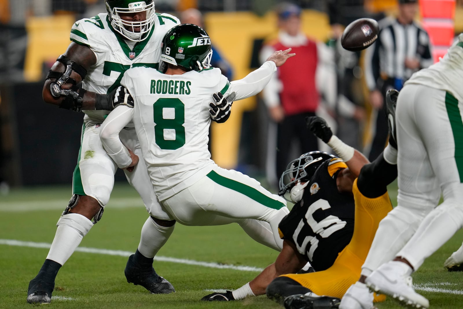 New York Jets quarterback Aaron Rodgers (8) tosses the ball as he is brought down by Pittsburgh Steelers linebacker Alex Highsmith (56) in the first half of an NFL football game in Pittsburgh, Sunday, Oct. 20, 2024. (AP Photo/Gene J. Puskar)