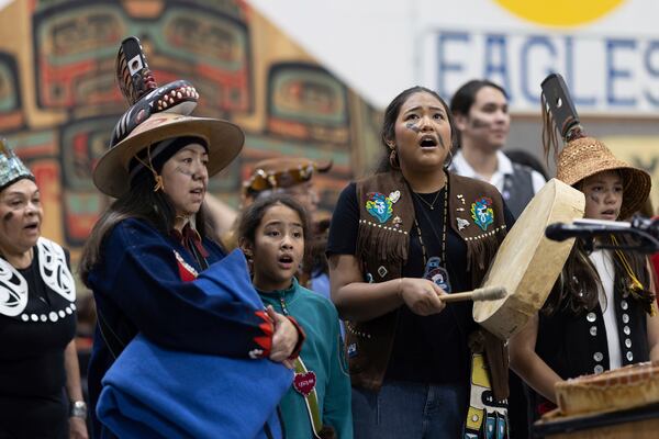 Angoon resident Shgen George and her daughters perform a ceremonial song during a U.S. Navy ceremony Saturday, Oct. 26, 2024, in Angoon, Alaska, to apologize for the 1882 military bombing of the Tlingit village in Angoon. (Nobu Koch/Sealaska Heritage Institute via AP)