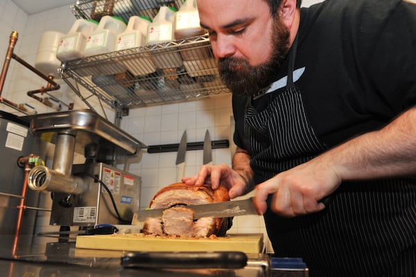 141229-ATLANTA-GA- Dine review of Todd Ginsbergs new counters Yalla and Fred's Meat & Bread, inside the Krog St Market, on Thursday January 1, 2015. Todd slices pork for the porchetta at Fred's Meat & Bread. (Beckysteinphotography.com) Todd Ginsberg cutting a porchetta at Fred's