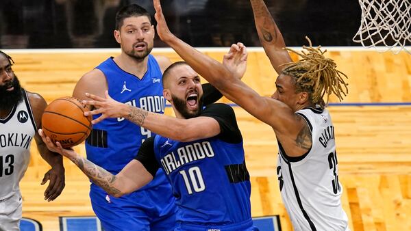 Orlando Magic guard Evan Fournier (10) goes up for a shot as he gets between Brooklyn Nets guard James Harden (13) and forward Nicolas Claxton as Orlando Magic center Nikola Vucevic, back center, looks on during the second half of an NBA basketball game, Friday, March 19, 2021, in Orlando, Fla. (AP Photo/John Raoux)