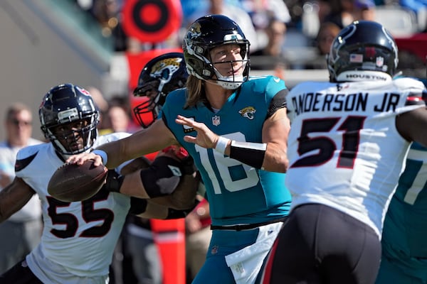 Jacksonville Jaguars quarterback Trevor Lawrence (16) throws a pass while he is pressured by Houston Texans defensive end Danielle Hunter (55) and defensive end Will Anderson Jr. (51) during the first half of an NFL football game Sunday, Dec. 1, 2024, in Jacksonville, Fla. (AP Photo/John Raoux)