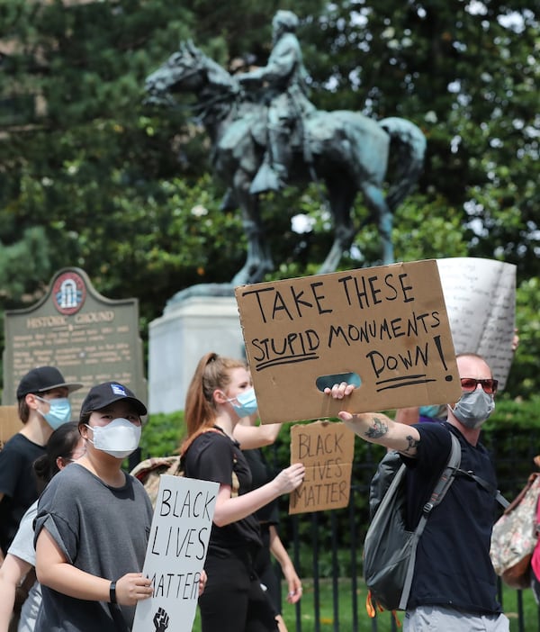 Grayson Campbell holds a sign calling for the removal of the bronze statue of John Brown Gordon in full Confederate regalia atop his horse Marye, seen behind him, while hundreds of protesters shout take it down at the Capitol Building after marching from Olympic Park following the Atlanta police shooting death of Rayshard Brooks outside of Wendy’s and the death of George Floyd at the hands of Minneapolis police officers on Sunday, June 14, 2020, in Atlanta. Unveiled in 1907, the statue of the former Georgia governor and U.S. senator is one of the most controversial monuments to the Old South on the Capitol grounds, and is frequently at the center of protests and calls for removal. CURTIS COMPTON / CCOMPTON@AJC.COM