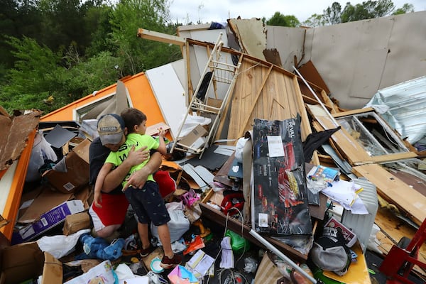 Randy Shoemaker embraces his son Conner, 6, after the family survived a deadly tornado that killed at least 7 in Murray County on April 12, in Chatsworth. Shoemaker, his wife Kimberly, son Conner, and daughter Isabella, 4, survived by covering themselves with mattresses in the bathroom of their mobile home while the roof was lifted off and the rest of the trailer flattened.