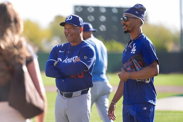 Los Angeles Dodgers manager Dave Roberts, left, and shortstop Mookie Betts greet guests during a spring training baseball practice, Thursday, Feb. 27, 2025, in Phoenix. (AP Photo/Ashley Landis)