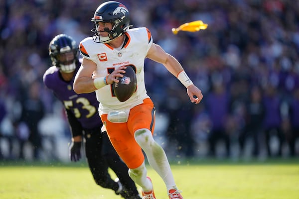 Denver Broncos quarterback Bo Nix, front, eludes a tackle by Baltimore Ravens linebacker Kyle Van Noy, back, in the first half of an NFL football game Sunday, Nov. 3, 2024, in Baltimore. (AP Photo/Stephanie Scarbrough)