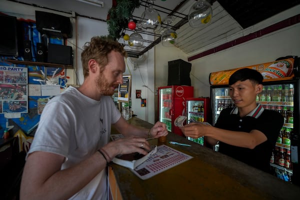 A foreign tourist buys coffee at Nana Backpack hostel bar in Vang Vieng, Laos, Tuesday, Nov. 19, 2024. (AP Photo/Anupam Nath)