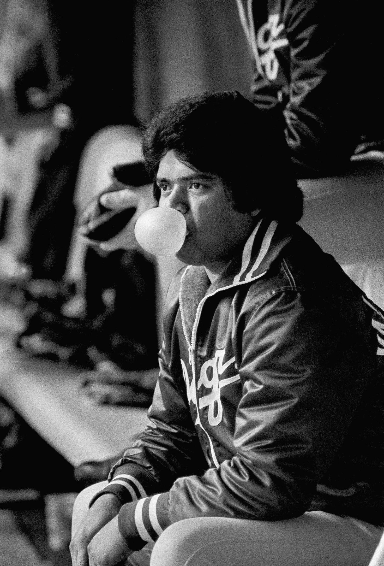 FILE - Los Angeles Dodgers pitcher Fernando Valenzuela blows bubbles as he passes the time in the dugout during the rain delay before Game 3 of the National League playoffs with the Expos at Montreal, Oct. 18, 1981. Fernando Valenzuela, the Mexican-born phenom for the Los Angeles Dodgers who inspired “Fernandomania” while winning the NL Cy Young Award and Rookie of the Year in 1981, has died Tuesday, Oct. 22, 2024.(AP Photo/Rusty Kennedy, File)