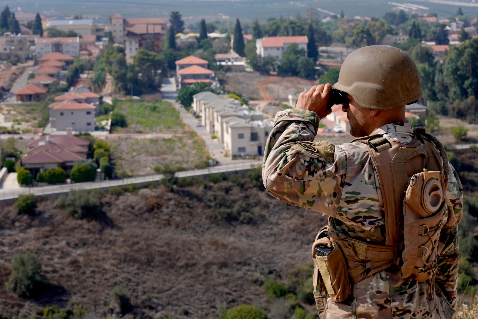 FILE - A Lebanese soldier looks through his binoculars into the Israeli town of Metula at the Lebanese side of the border in the southern village of Kfar Kila, Lebanon, Sunday, Oct. 8, 2023. (AP Photo/Hussein Malla, File)