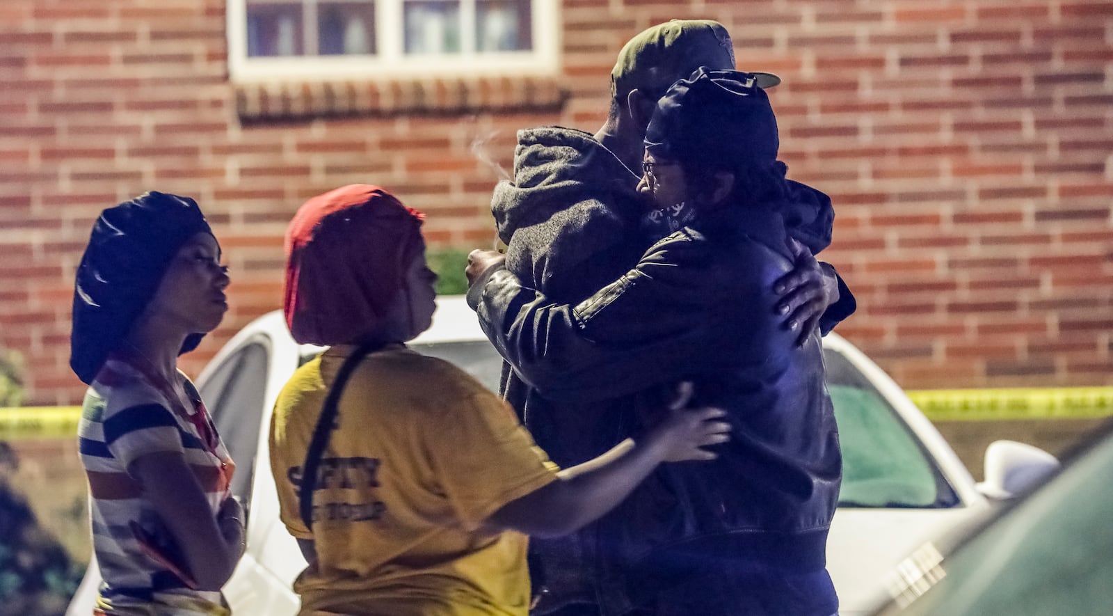 Onlookers grieve after Eva Jones, 59, was fatally shot in the fourth homicide in 59 days at Pavilion Place in Atlanta. Jones was sleeping when bullets from an AR-15-style weapon tore through her first floor apartment. The gunfire shattered windows and ripped up flooring. Police said she was not the intended target. (John Spink / AJC 2020)