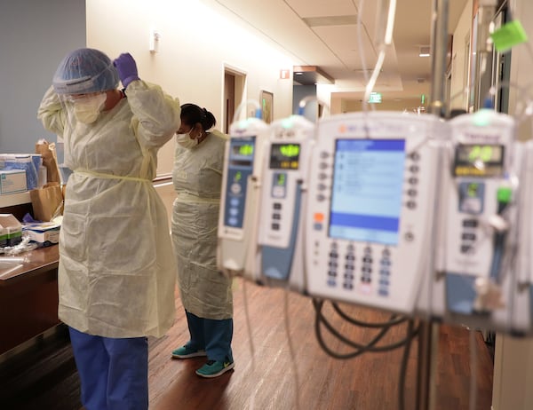 In this file photo, ICU nurse Samantha Lazzara, left, and Judith Mclean, right, a patient care technician, put on PPE gear before entering a COVID-19 patient's room in the ICU unit at Northwestern Medicine Lake Forest Hospital on Friday, Oct. 1, 2021, in Lake Forest, Illinois. (Stacey Wescott/Chicago Tribune/TNS)