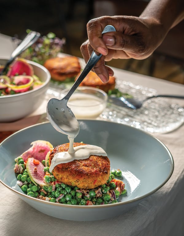 Buttermilk Dressing is drizzled onto Fresh Salmon Croquettes With Spring Pea, Bacon, and Radish Salad in this image from "The Twisted Soul Cookbook: Modern Soul Food With Global Flavors" (Rizzoli New York, 2021) by Deborah VanTrece. Courtesy of Noah Fecks