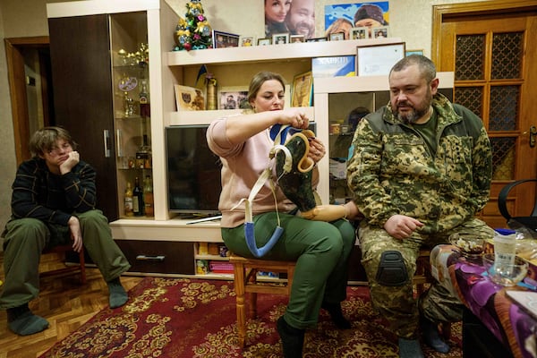 Oleksandr Puzikov, a captain with Ukraine's 127th brigade who lost an arm in combat, and his wife, Iryna, look at an arm prosthesis in their apartment in Kharkiv, Ukraine, on Feb. 3, 2025. (AP Photo/Evgeniy Maloletka)