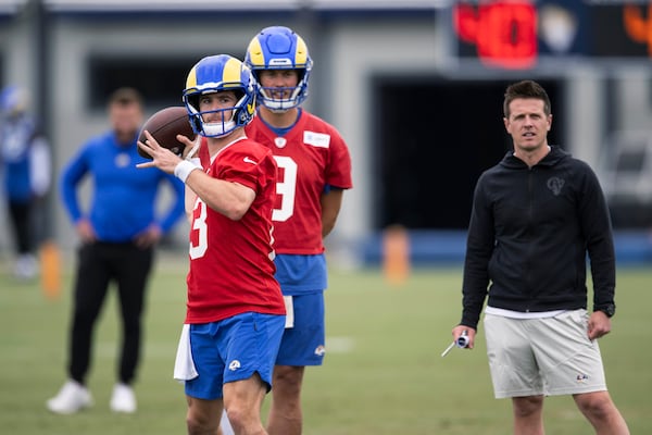 Los Angeles Rams quarterback Stetson Bennett, left, throws a pass as quarterback Matthew Stafford, center, and offensive coordinator Mike LeFluer watch during the NFL football team's camp Wednesday, June 14, 2023, in Thousand Oaks, Calif. (AP Photo/Kyusung Gong)