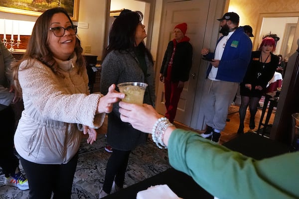 A guest is handed a Kiwi Mule mocktail, made without tequila, during the sober Saint Patrick's Day celebration at the Whistler House Museum, Thursday, March 13, 2025, in Lowell, Mass. (AP Photo/Charles Krupa)