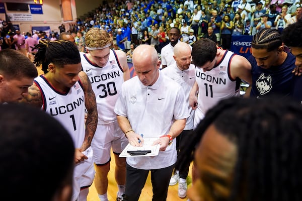 UConn head coach Dan Hurley huddles with his team, including guard Solo Ball (1), forward Liam McNeeley (30) and forward Alex Karaban (11) before facing Memphis in an NCAA college basketball game at the Maui Invitational Monday, Nov. 25, 2024, in Lahaina, Hawaii. (AP Photo/Lindsey Wasson)