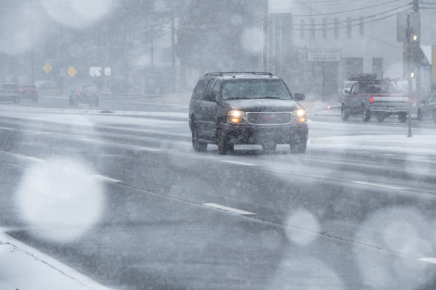 An SUV makes its way down Lawrenceville Highway in Decatur as snow begins to cover the road Tuesday, Jan. 21, 2025. (Ben Gray for the Atlanta Journal-Constitution)