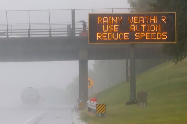 A person walks with an umbrella as interstate traffic slows during heavy rain in Atlanta on Thursday.