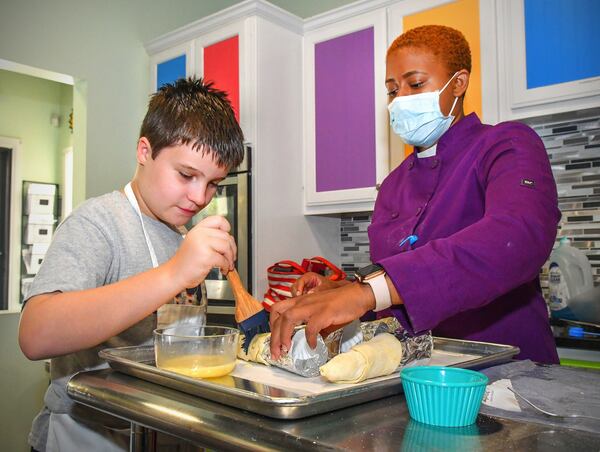 Student Connor Kolwaite, 10, of Auburn, Ala., adds an egg wash to the cream horn he made just prior to baking, as Young Chefs Academy instructor Christina Glass looks on during a recent class. CONTRIBUTED BY CHRIS HUNT PHOTOGRAPHY