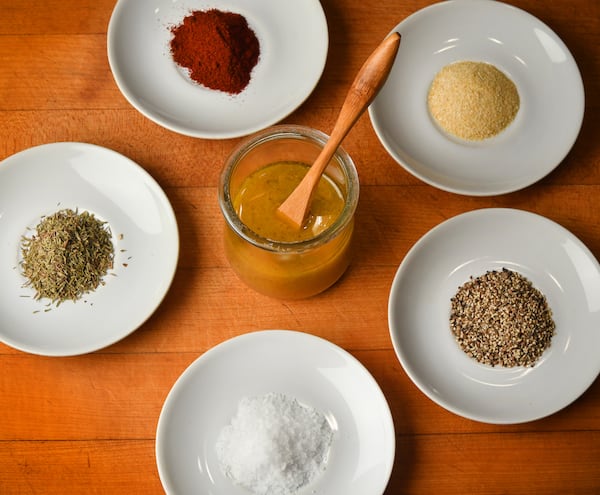 Make your own vinaigrette (center) with a 3-to-1 oil-to-vinegar ratio, shown here with the components of the All-Purpose Seasoning Blend: (clockwise from left) thyme, paprika, garlic and onion powder, black pepper and kosher salt. 
(Styling by Jennifer Hill Booker / Chris Hunt for The Atlanta Journal-Constitution) 