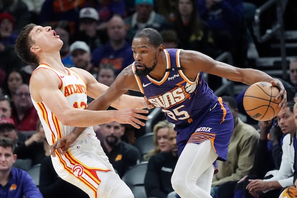 Phoenix Suns forward Kevin Durant (35) fouls Atlanta Hawks guard Bogdan Bogdanovic, left, during the first half of an NBA basketball game Thursday, Jan. 9, 2025, in Phoenix. (AP Photo/Ross D. Franklin)