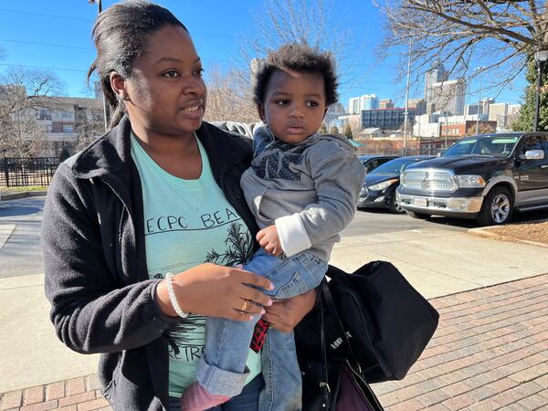 Lena Harris holds one of her children as she and her family prepare to get on a bus outside at city of Atlanta warming station at Serena S. Butler Park. The shuttle would take Harris and her five children, ages 1 to 10 years old, to another shelter. The family has been homeless in metro Atlanta for about a year. Matt Kempner/ AJC