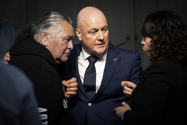 New Zealand's Prime Minister Christopher Luxon, center, talks with survivor Whiti Ronaki, left, and Laura Cherrington following his "formal and unreserved" apology in Parliament for the widespread abuse, torture and neglect of hundreds of thousands of children and vulnerable adults in care, in Wellington, New Zealand Tuesday, Nov. 12, 2024. (Monique Ford/Stuff via AP)