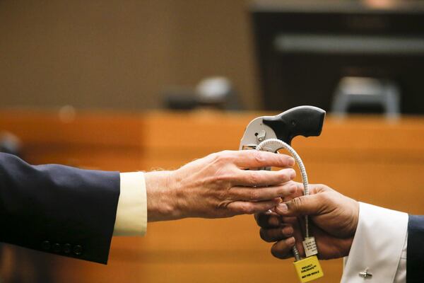 Crime scene analyst Ross Martin Gardner, left, hands back the gun used in the shooting of Diane McIver to Fulton County Chief Assistant District Attorney Clint Rucker during Day 19 of the Tex McIver murder trial in Fulton County Superior Court on Friday, April 13, 2018. (ALYSSA POINTER/ALYSSA.POINTER@AJC.COM)