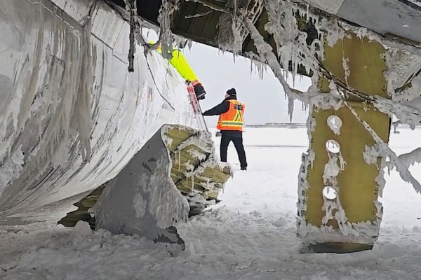 In this image provided by the National Transportation Safety Board, investigators examine the wreckage of a Delta Air Lines jet on Wednesday, Feb. 19, 2025, that burst into flames and flipped upside down as it tried to land on Feb. 17, at Toronto Pearson International Airport in Mississauga, Ontario. (National Transportation Safety Board via AP)