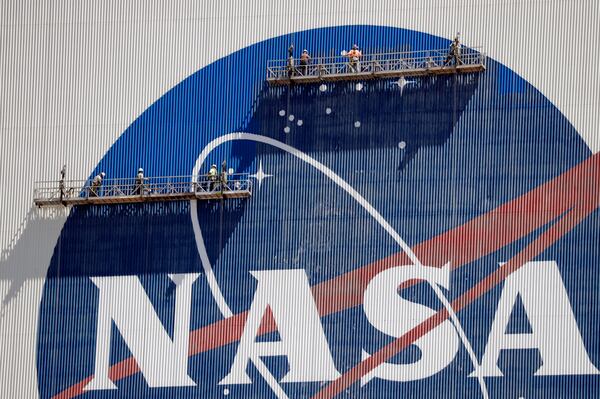 Workers near the top of the Vehicle Assembly Building at the Kennedy Space Center spruce up the NASA logo.