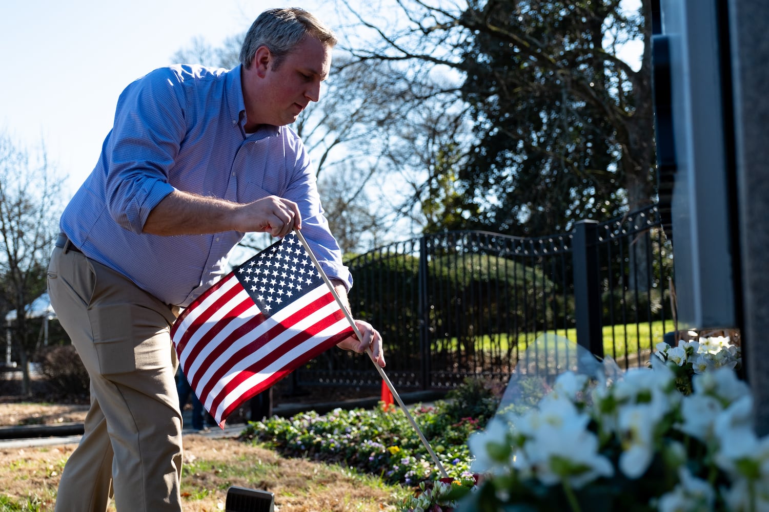 Donovan Head, of Woodstock, places a flag and flowers at a makeshift memorial to former President Jimmy Carter at the Carter Center in Atlanta on Monday, Dec. 30, 2024. Head had met Carter a few times and said he had a huge impact on him.  Ben Gray for the Atlanta Journal-Constitution